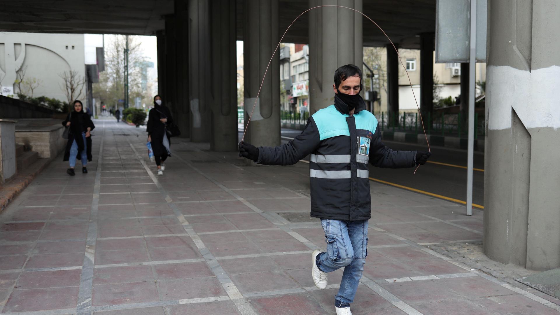 A man wearing a protective face mask and gloves, amid fear of coronavirus disease (COVID-19), jumps rope at Valiasr street in Tehran, Iran, March 26, 2020. 