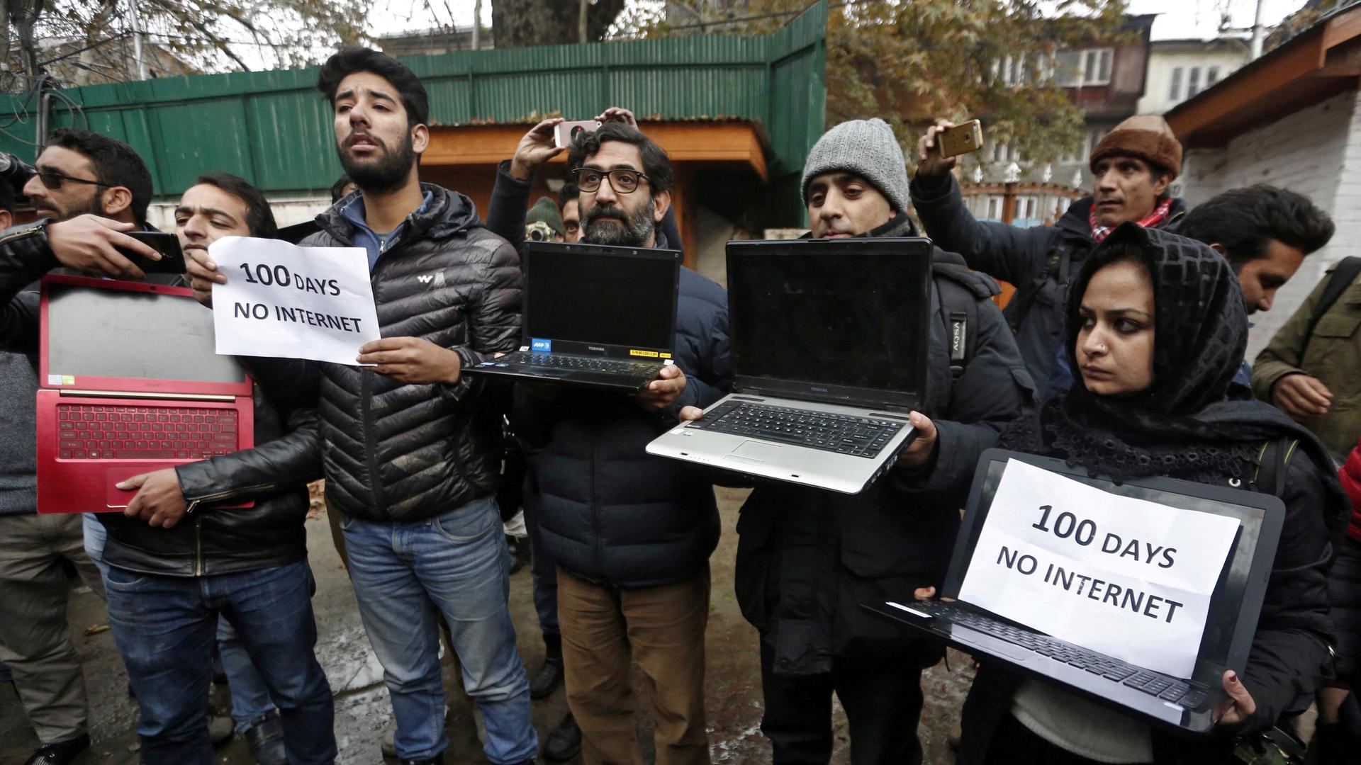 Kashmiri journalists display laptops and placards during a protest demanding restoration of internet service, in Srinagar, Nov. 12, 2019. 
