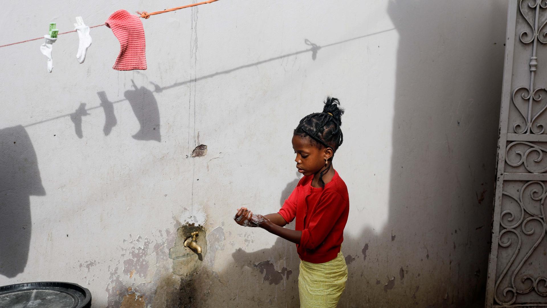 A girl washes her hands at a spigot at the entrance of her parents' house in Pikine, on the outskirts of Dakar, Senegal, on March 9, 2020.