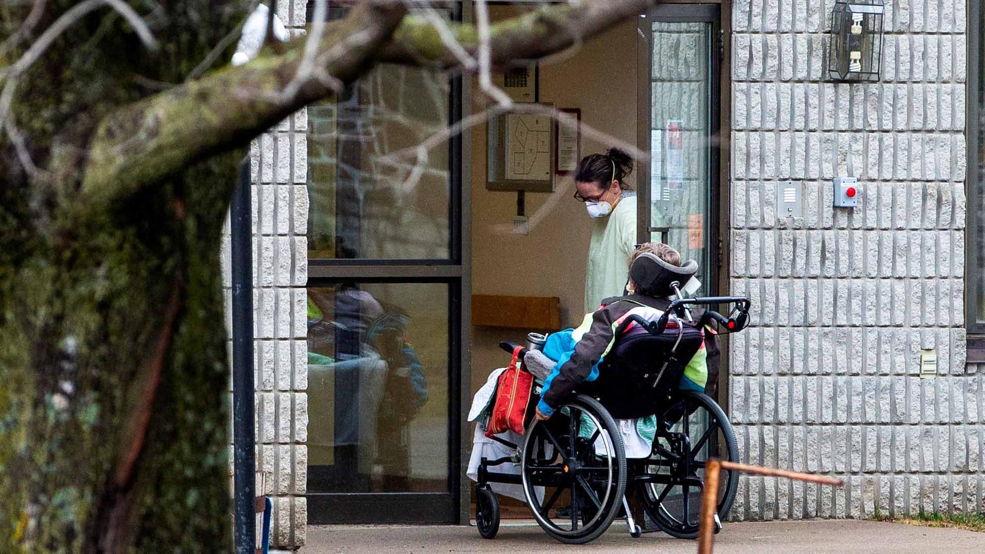 A woman opens the door to a person in a wheelchair at Pinecrest Nursing Home after several residents died and dozens of staff were sickened due to the coronavirus disease (COVID-19), in Bobcaygeon, Ontario, Canada, on March 30, 2020.