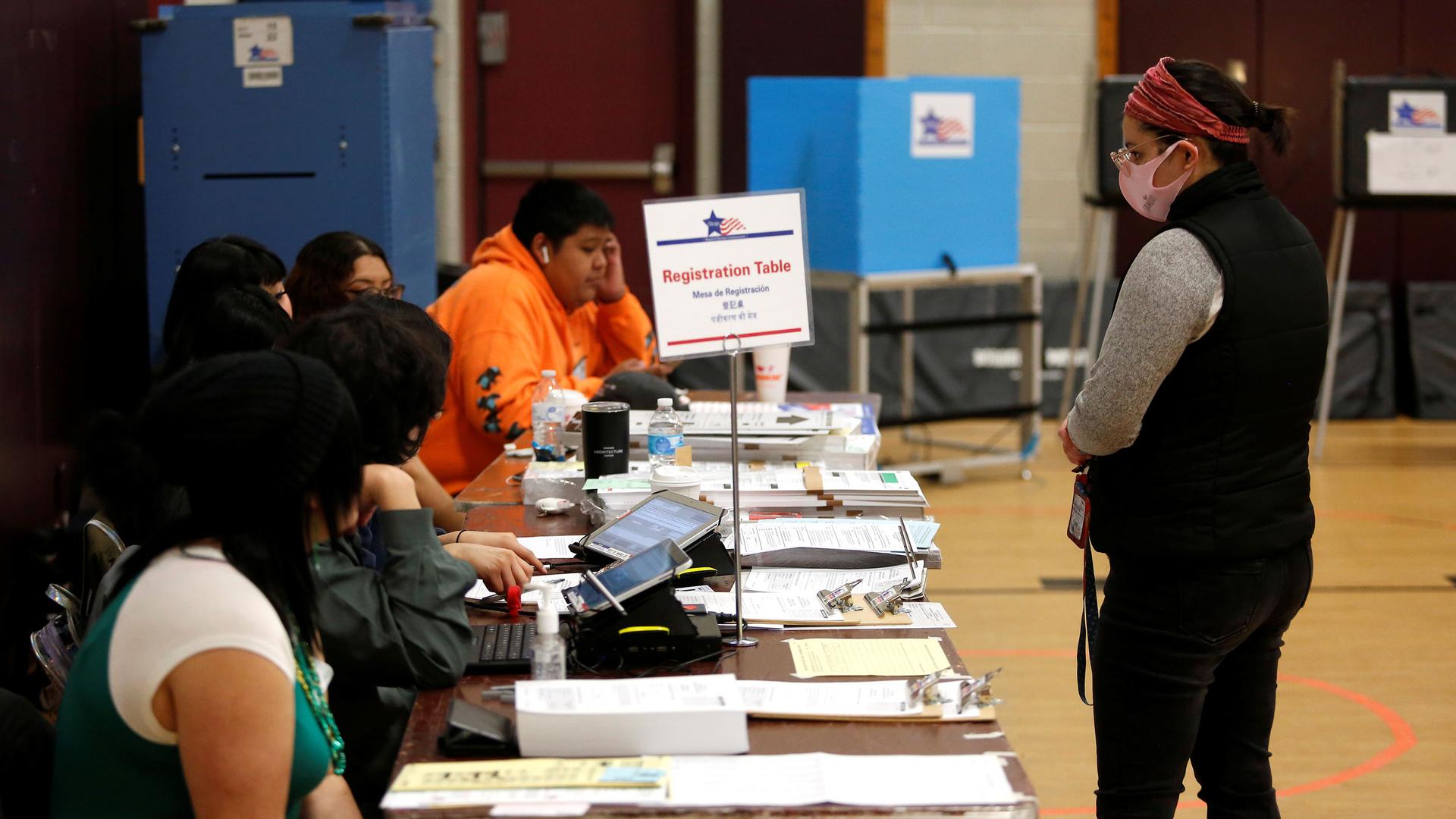 A voter stands at the registration table before receiving their ballot during the Democratic presidential primary election at Madero Middle School in Chicago, Illinois, March 17, 2020.