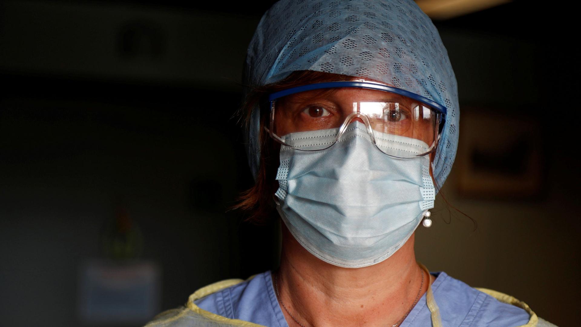 A close-up photograph of a doctor a wearing protective face mask and goggles.