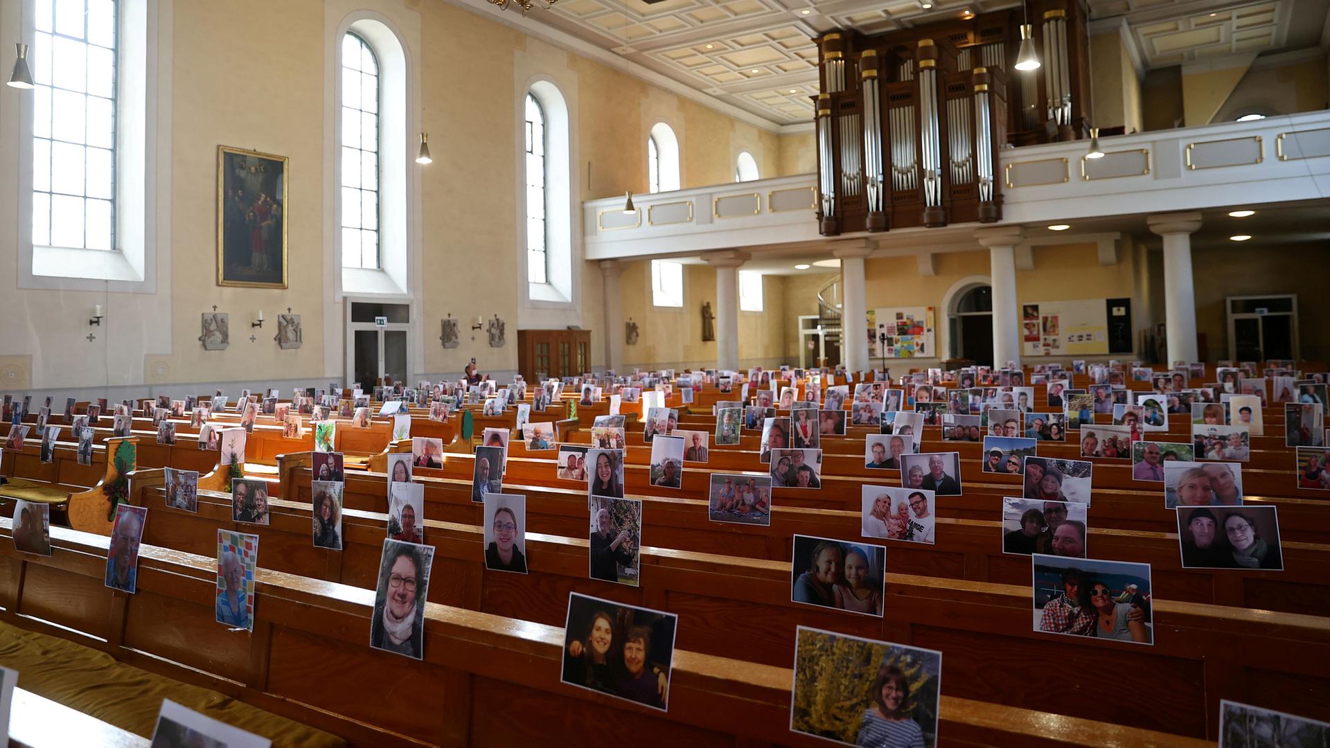 A church sanctuary is shown with empty rows of pews and the photos of people's faces taped to the back rest.