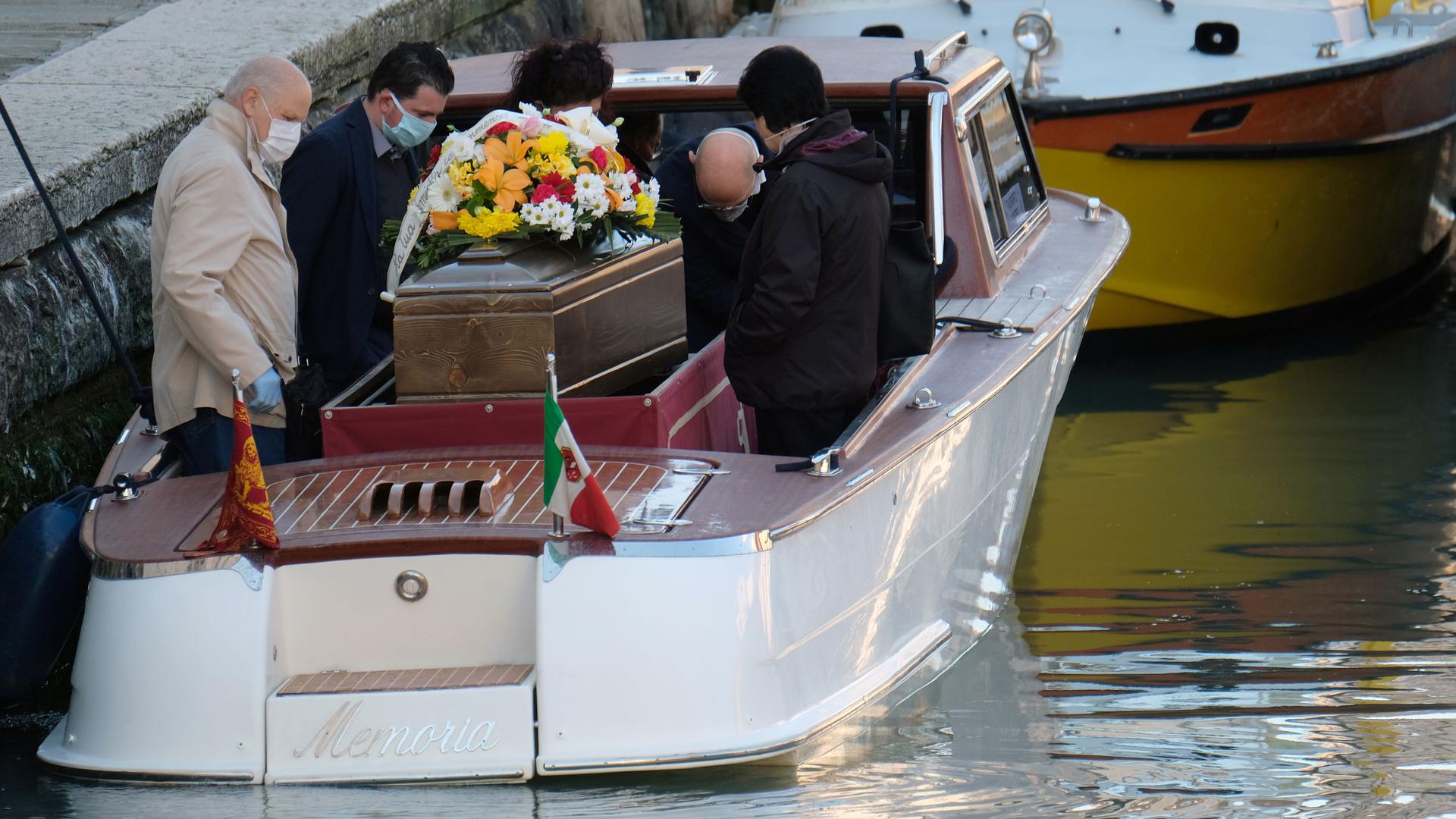 People gather around a coffin on a boat