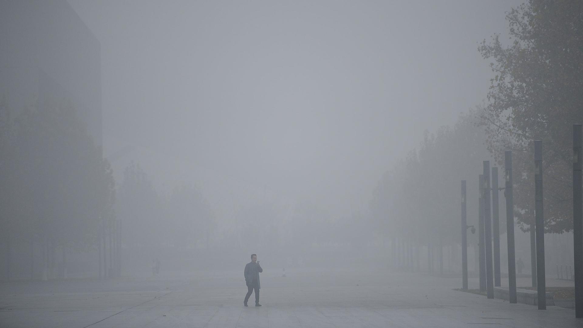 A man in the middle of a smog-filled street