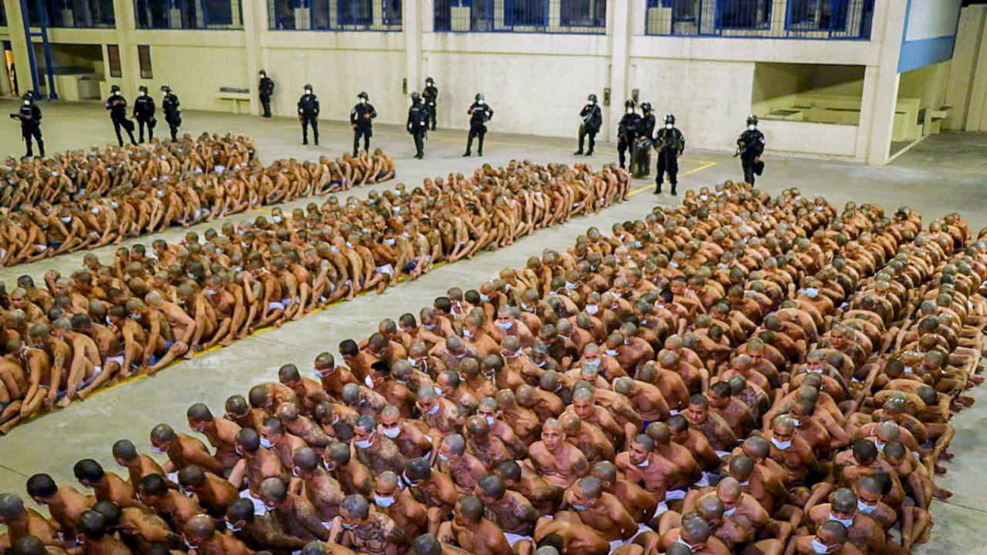 Hundreds of inmates are shown wearing only underware and sitting crammed together in rows.