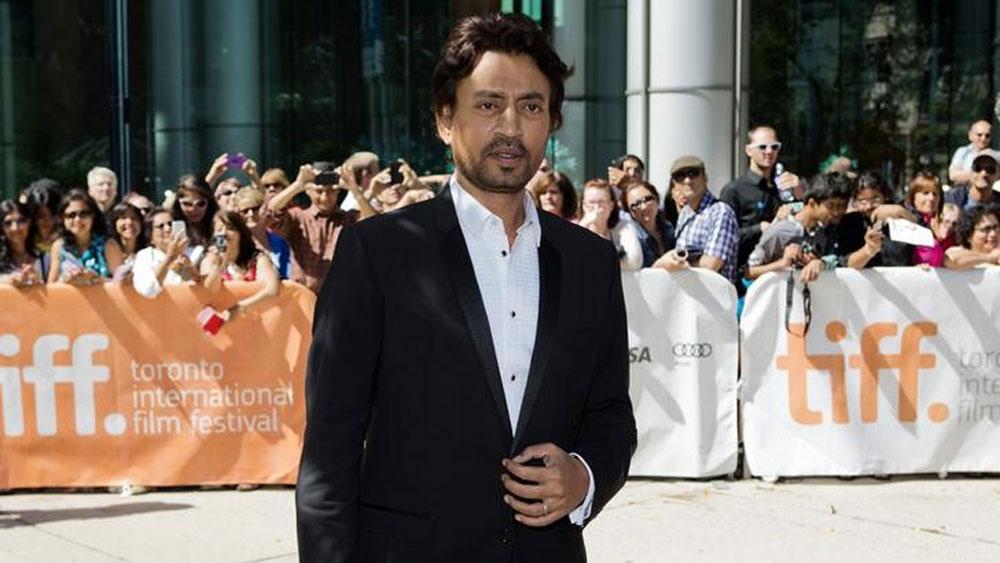 Indian actor Irrfan Khan is shown wearing a dark tuxedo with a crowd in the background.