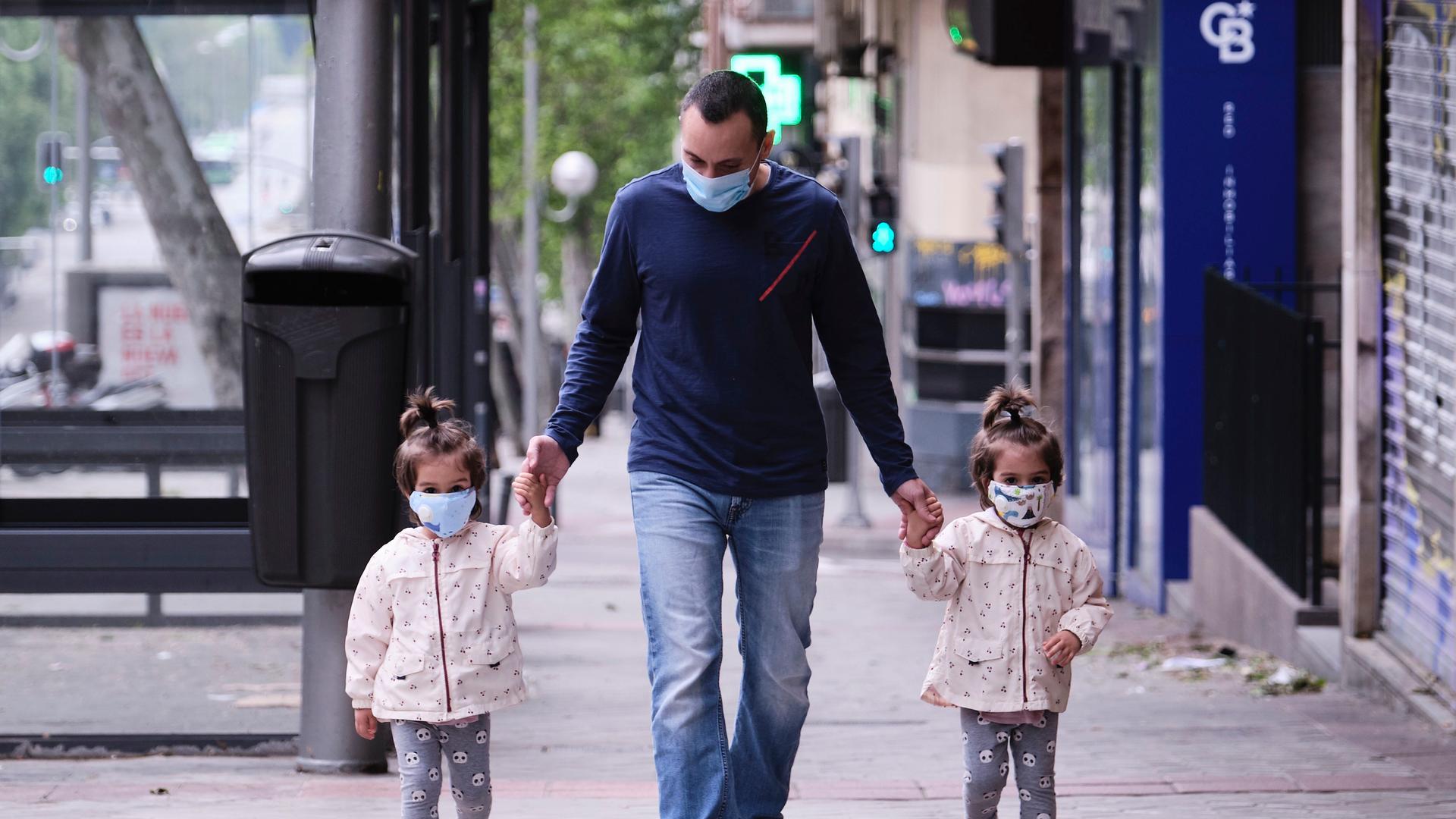 José Valdes takes his twin daughters out for a walk in Madrid on the day Spain lifts restrictions on children outdoors due to the coronavirus pandemic.