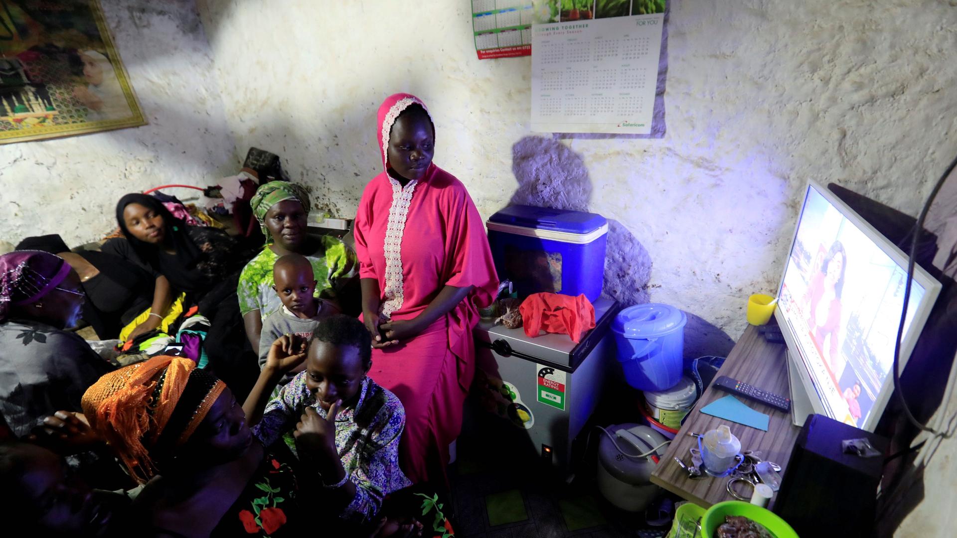 Residents watch a television at the beginning of a curfew which was ordered by the Kenya's President Uhuru Kenyatta to contain the spread of the coronavirus disease (COVID-19) inside a house within Kibera slums in Nairobi, Kenya, March 27, 2020.