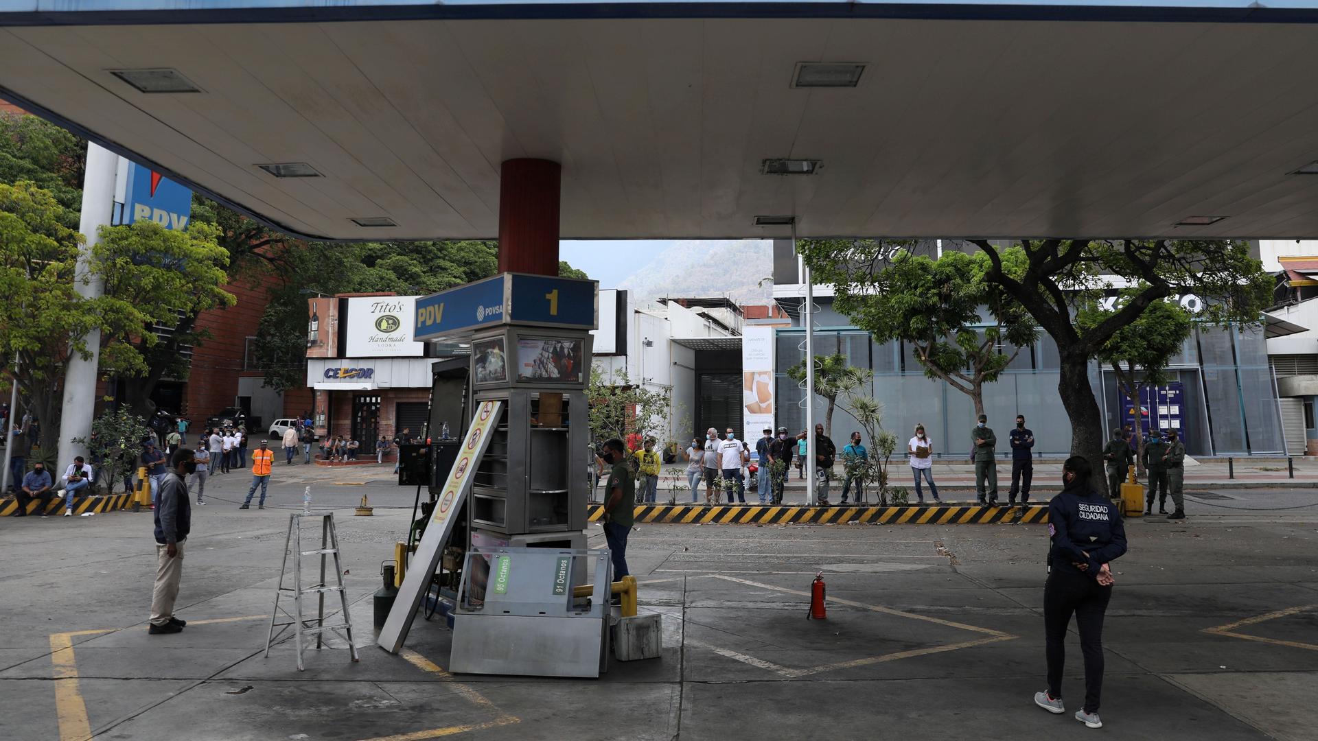 Customers wait while a fuel dispenser machine is fixed at a gas station in Caracas, Venezuela, April 23, 2020. 