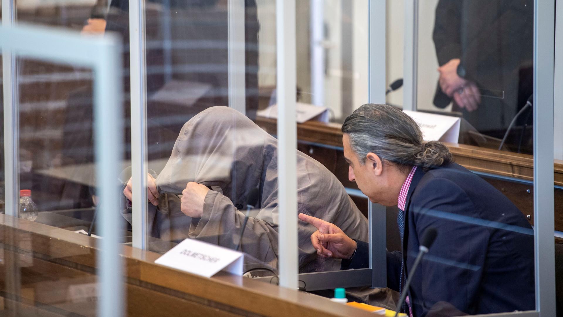Syrian defendant Eyad A. hides himself under his hood prior to the first trial of suspected members of Syrian President Bashar al-Assad's security services for crimes against humanity, in Koblenz, Germany, April 23, 2020.