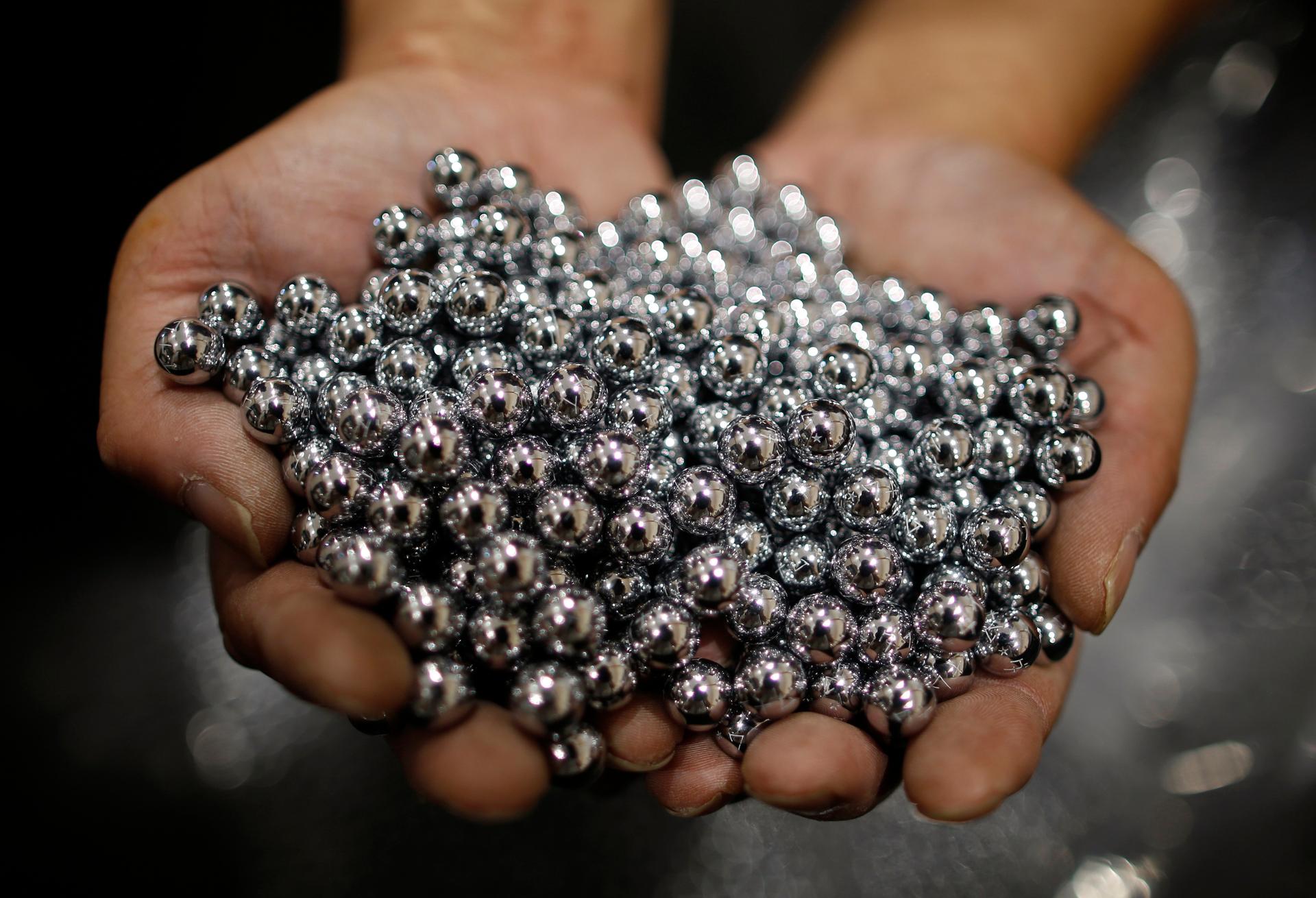 A worker holds silver pachinko balls at a pachinko parlour in Fukaya, north of Tokyo, July 15, 2014.
