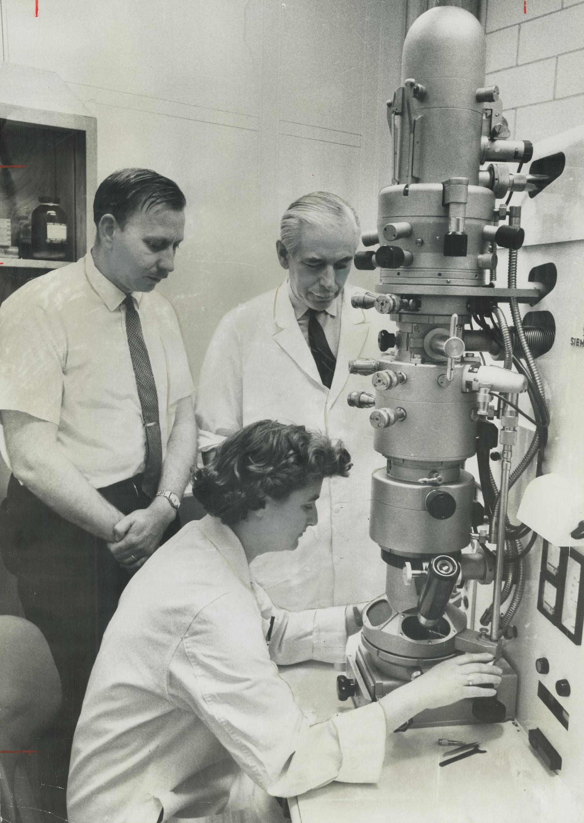 June Almeida, Scotish virologist looks into an electron microscope.