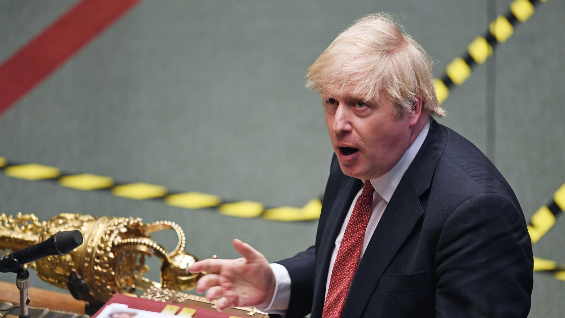 Britain's Prime Minister Boris Johnson is shown in a photograph from above standing at a podium with his hand outstretched.