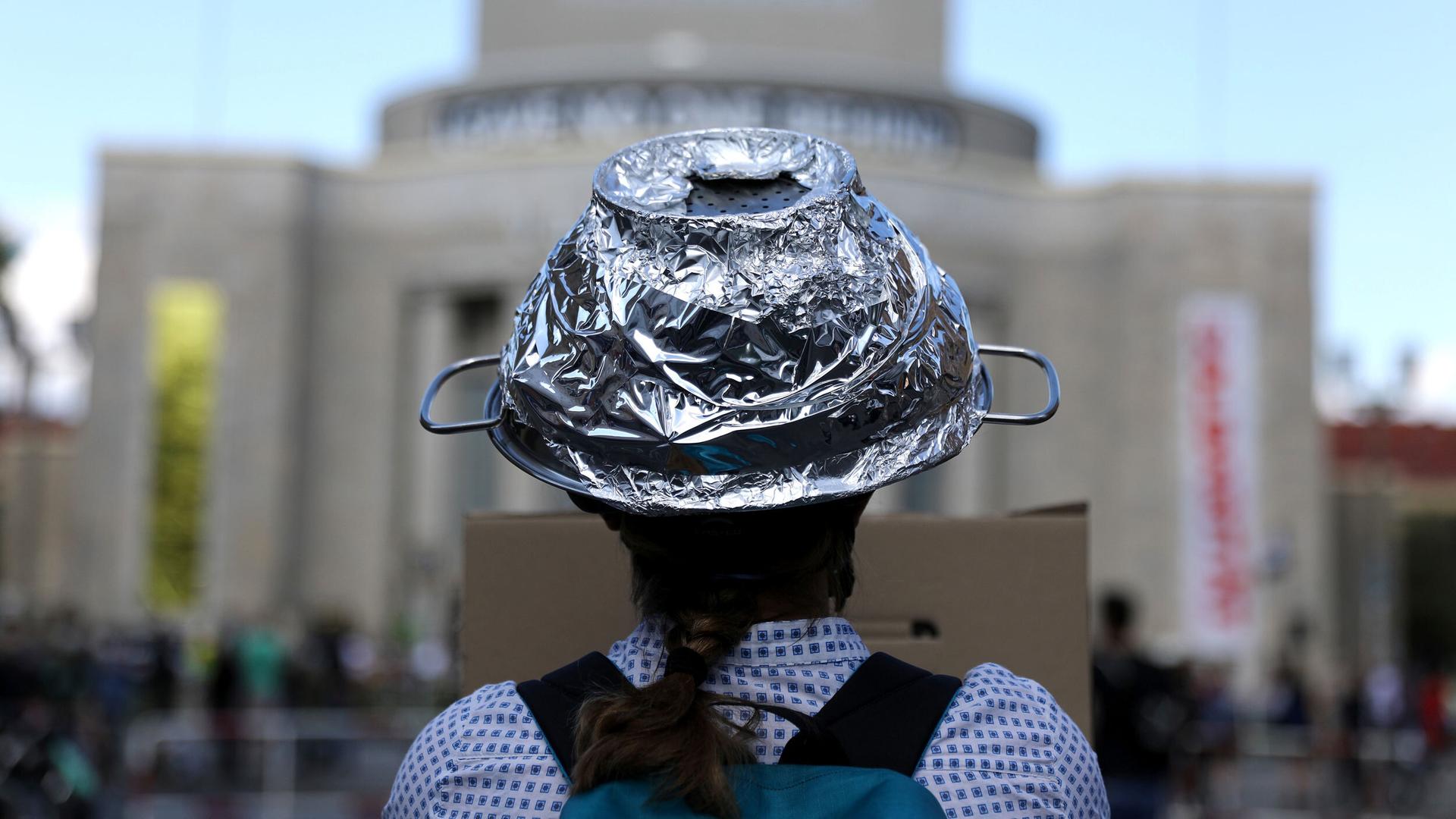 A woman is shown in a photograph from behind wearing a tin-foil hat.