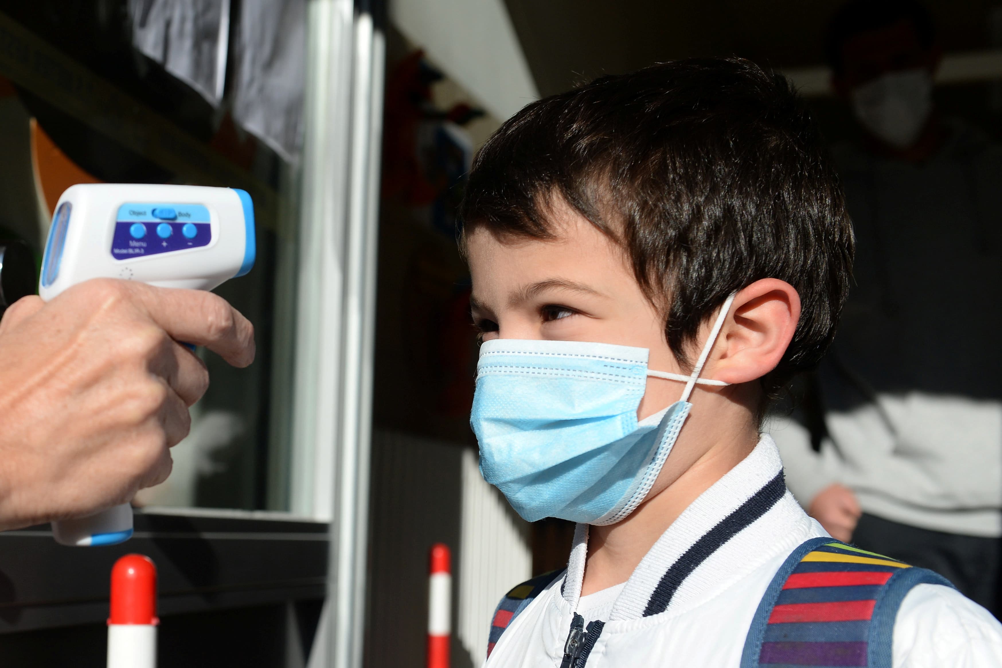 A teacher takes the children's temperature at the entrance of a flemish primary school during its reopening as a small part of Belgian children head back to their schools with new rules and social distancing during the outbreak of the coronavirus disease.