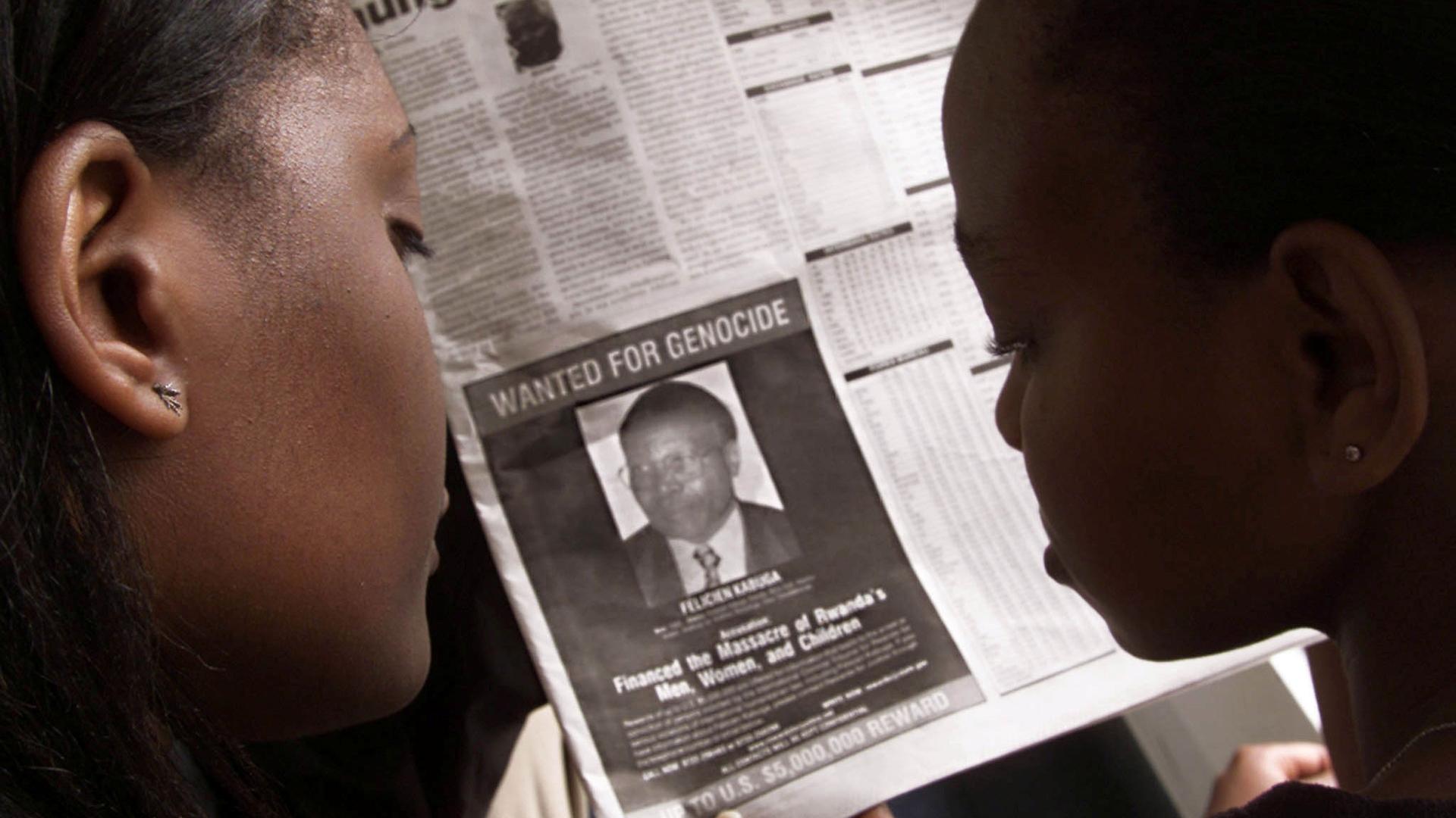 Two people are shown from behind looking at a newspaper featuring a photograph of Rwandan Felicien Kabuga.