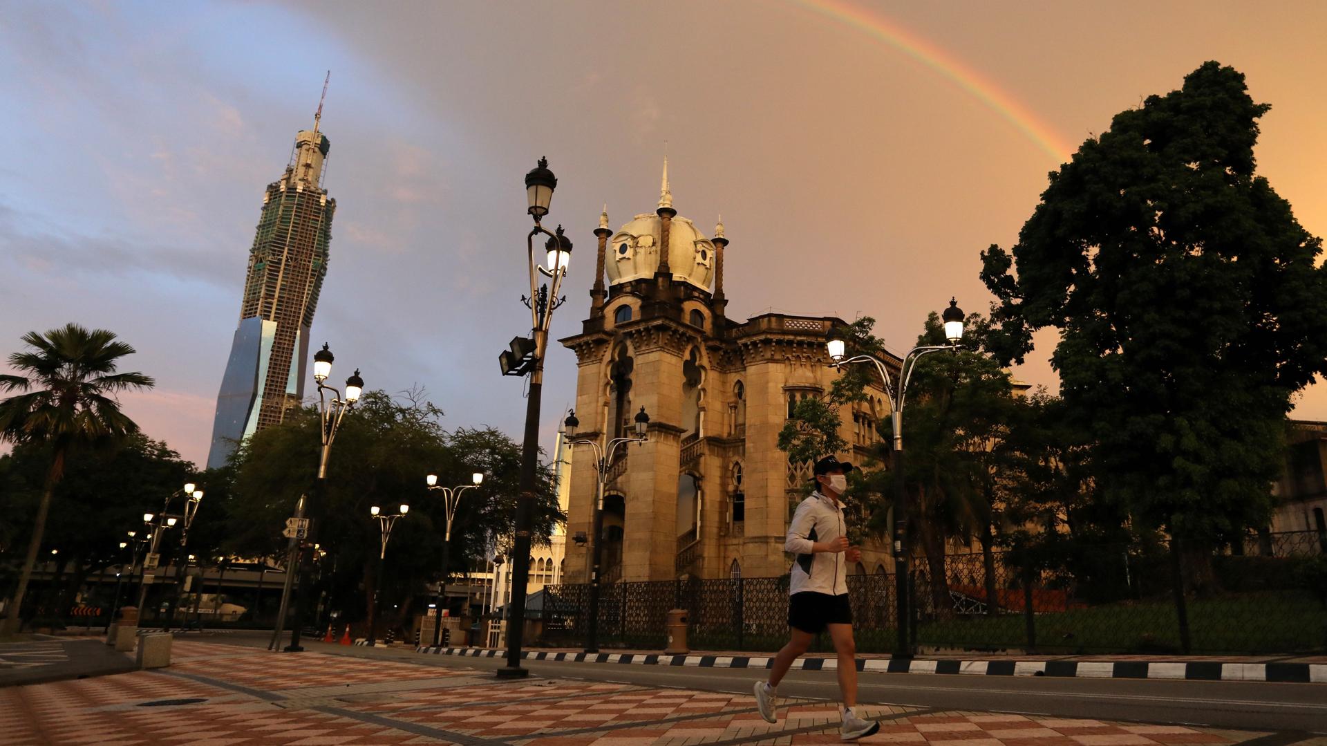 A man wearing protective face mask jogs under a rainbow as Malaysia reopens a majority of businesses, after a movement control order was imposed to fight the outbreak of the coronavirus disease (COVID-19), in Kuala Lumpur, Malaysia May 4, 2020. 