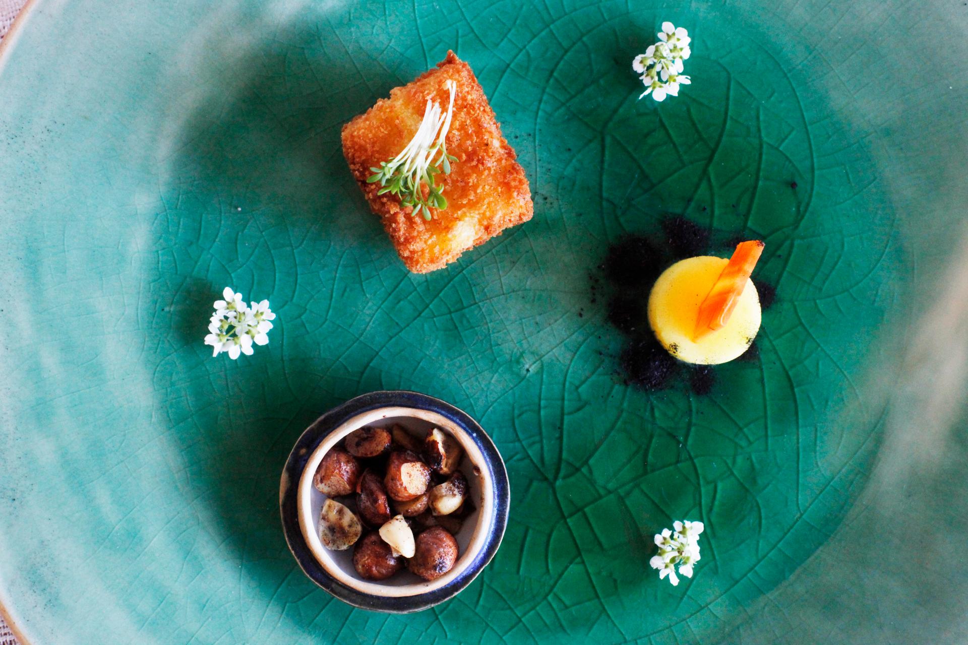 A poetic meal of three small dishes on a green plate