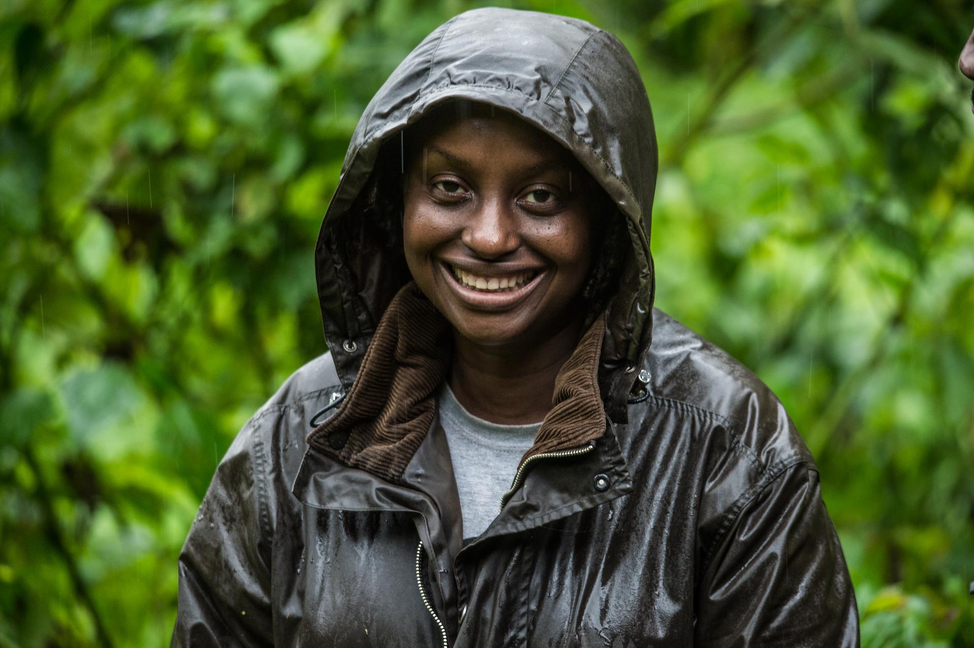 A woman wears a dark raincoat in the forest in Uganda