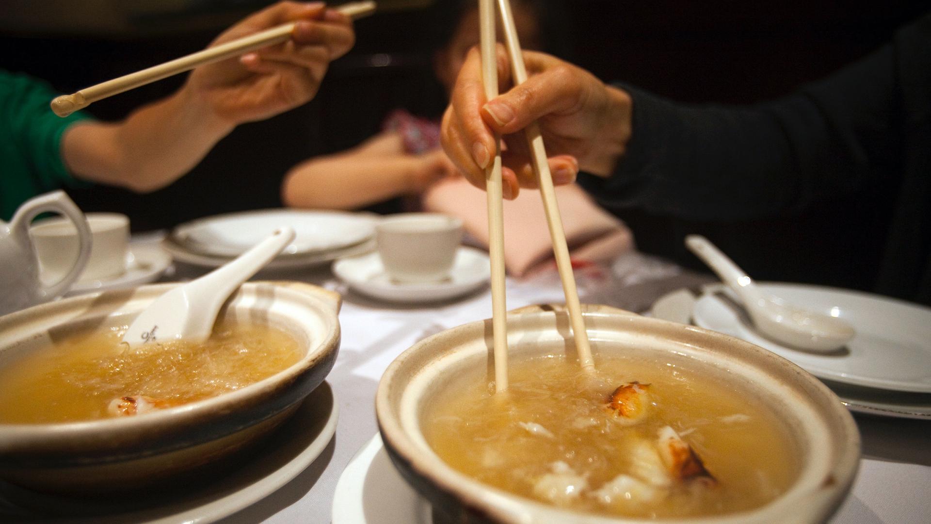 Two people eat with chopsticks at a restaurant