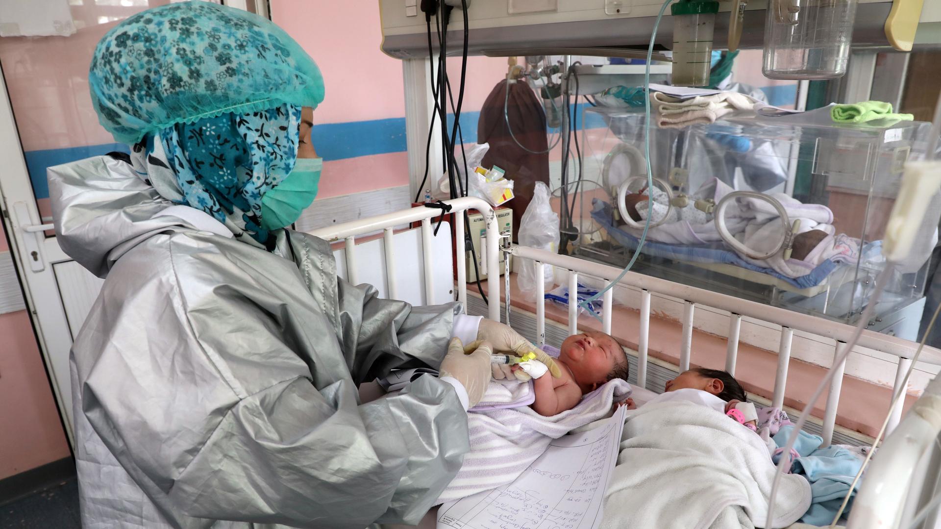 An Afghan nurse observes newborn children who lost their mothers during an attack at a hospital, in Kabul, May 13, 2020. 