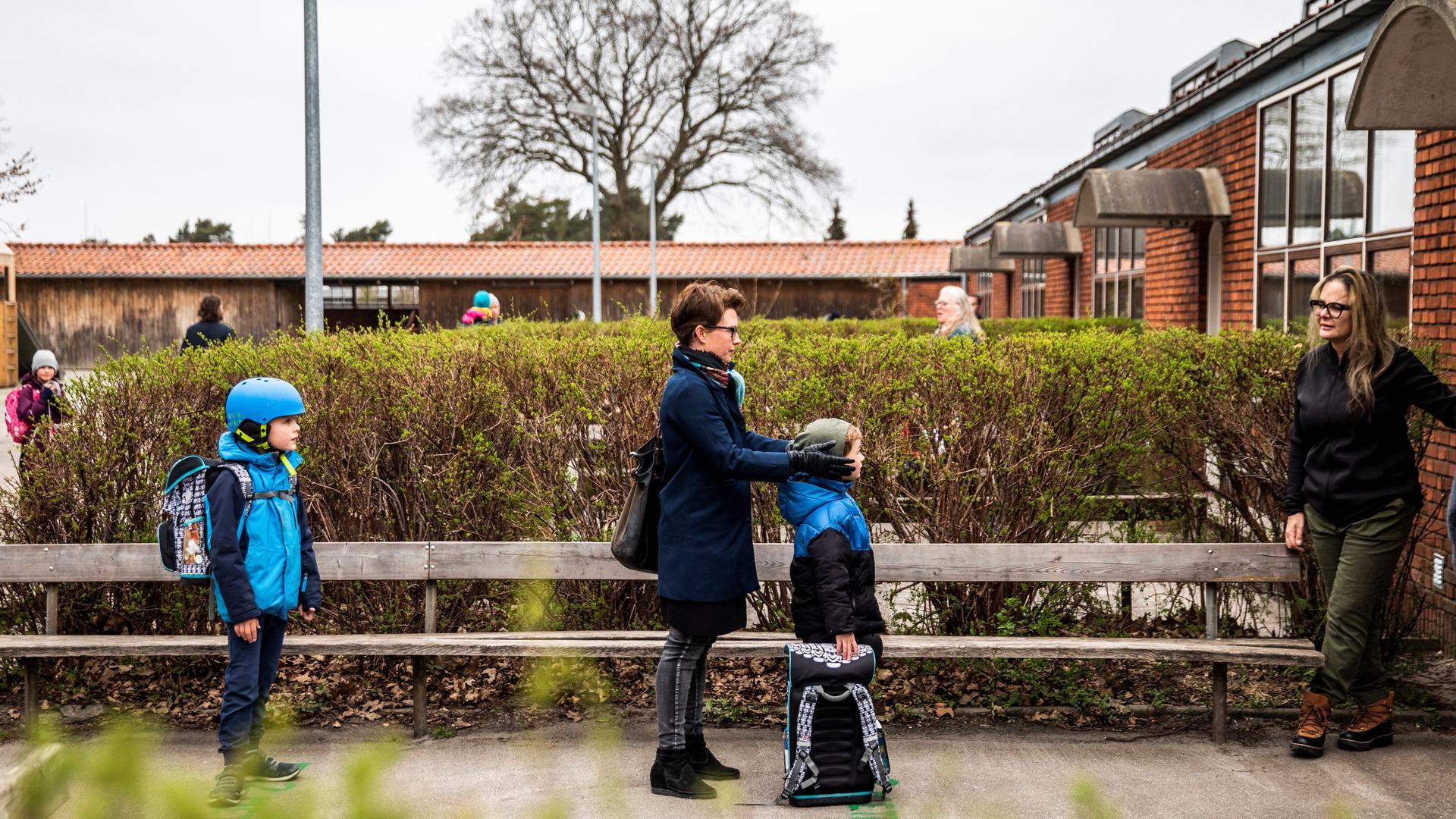 Parents with their children stand in a queue waiting to get inside Stengaard School following the coronavirus disease (COVID-19) outbreak north of Copenhagen, Denemark, April 15, 2020. 