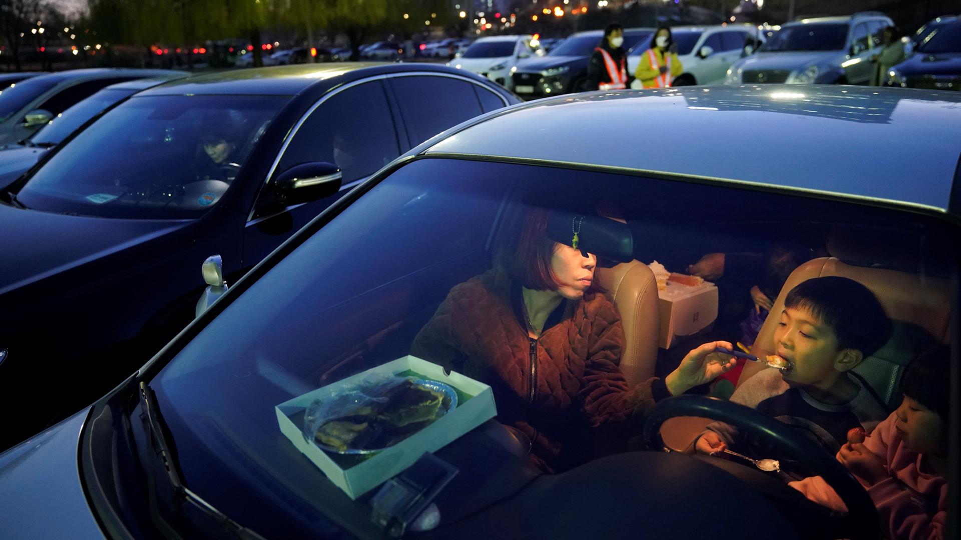 A woman feeds her child as they prepare to watch a movie from their car at a temporary made drive-in theater while keeping social distancing following the outbreak of the coronavirus disease (COVID-19), in Seoul, South Korea, March 27, 2020. 
