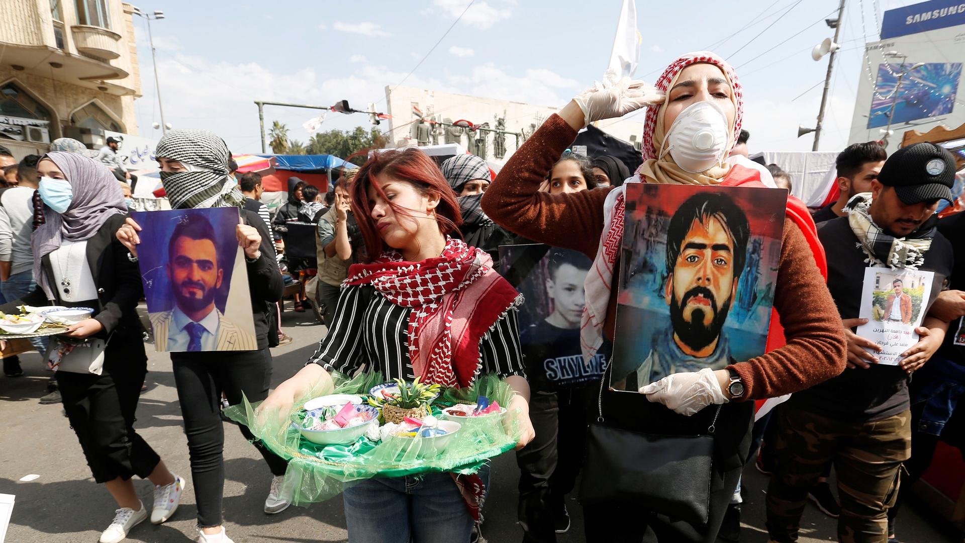 University students carry pictures of demonstrators who were killed during ongoing anti-government protests in Baghdad, March 1, 2020. 