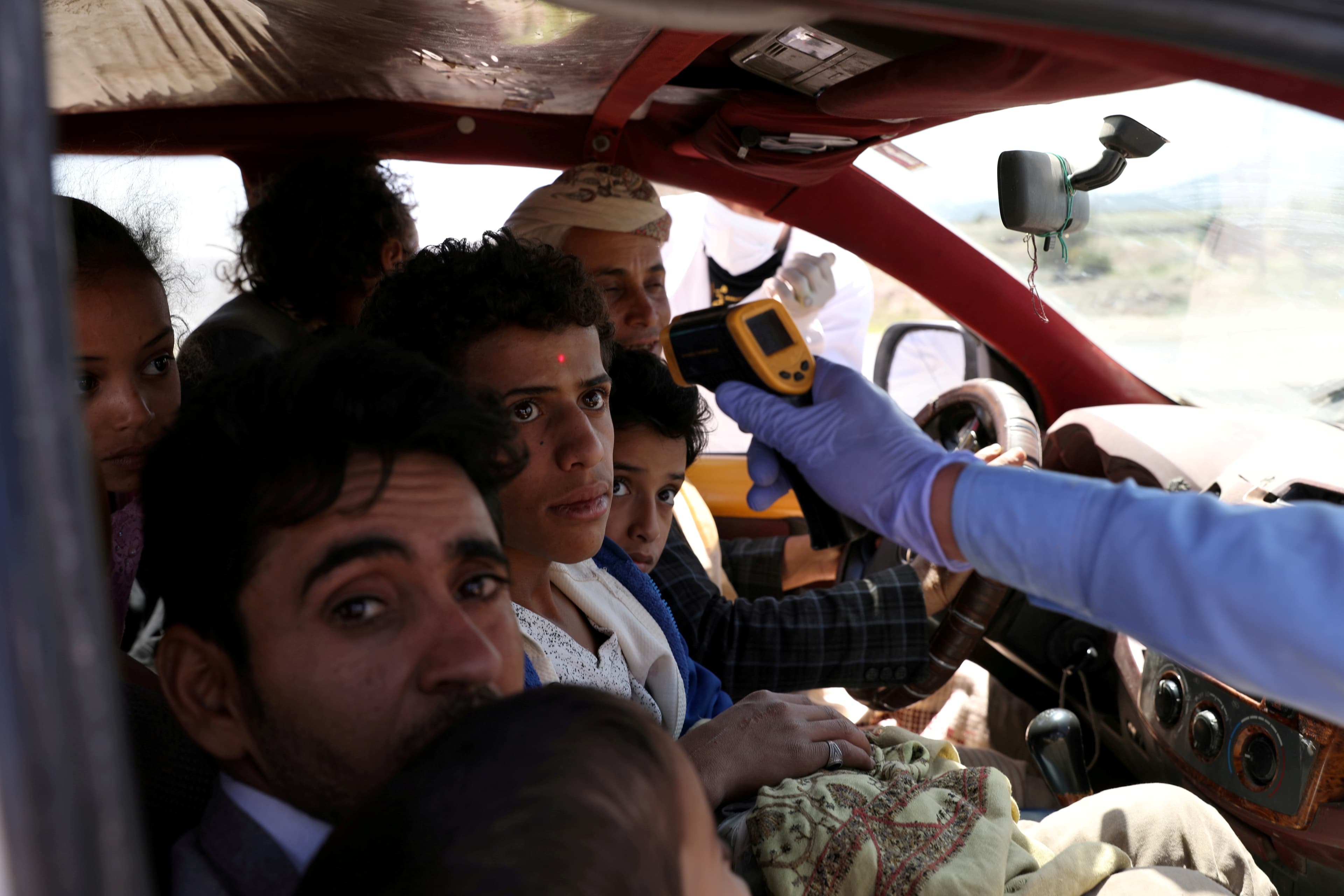 A health worker takes the temperature of people riding a taxi van