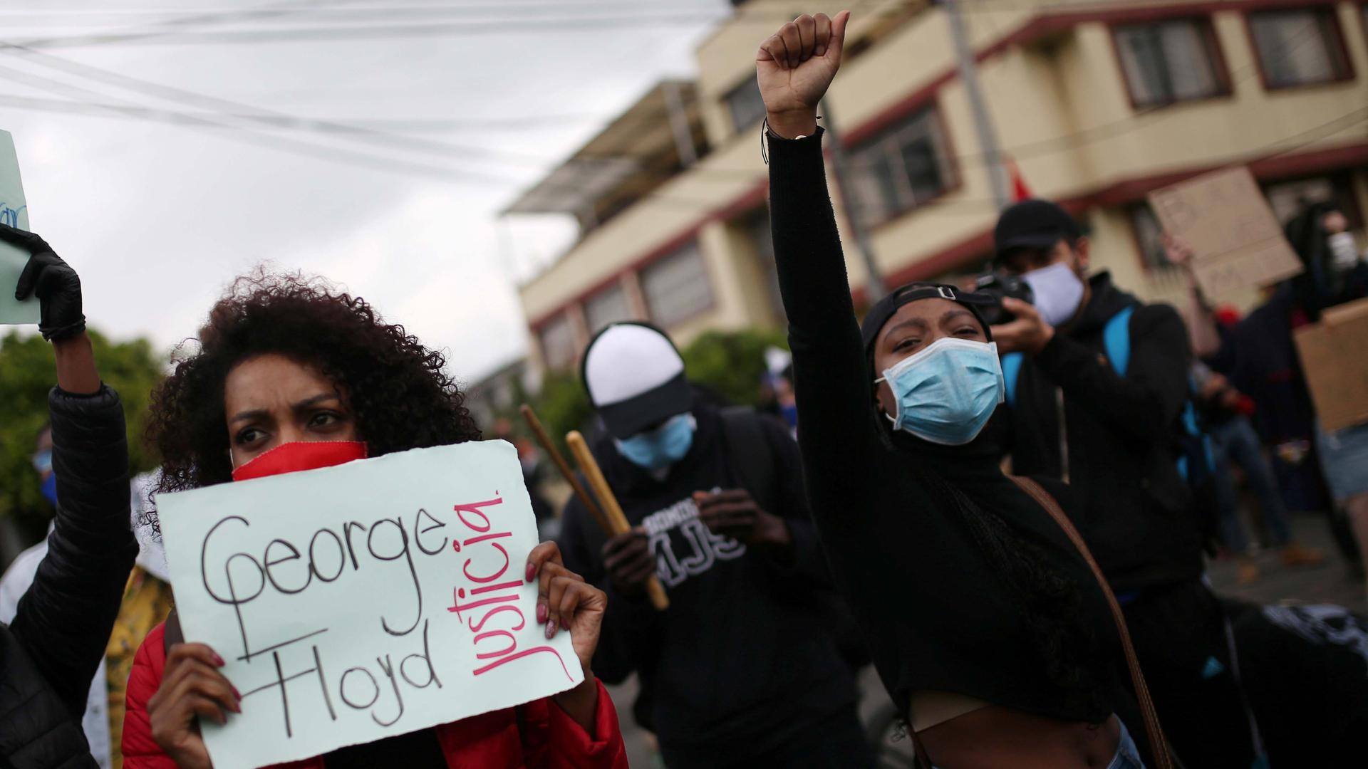 A demonstrator holds a sign that reads "George Floyd, justice" during a protest against the death in Minneapolis police custody of George Floyd and the arrival of US troops in Colombian territory, in Bogotá, Colombia, on June 3, 2020.