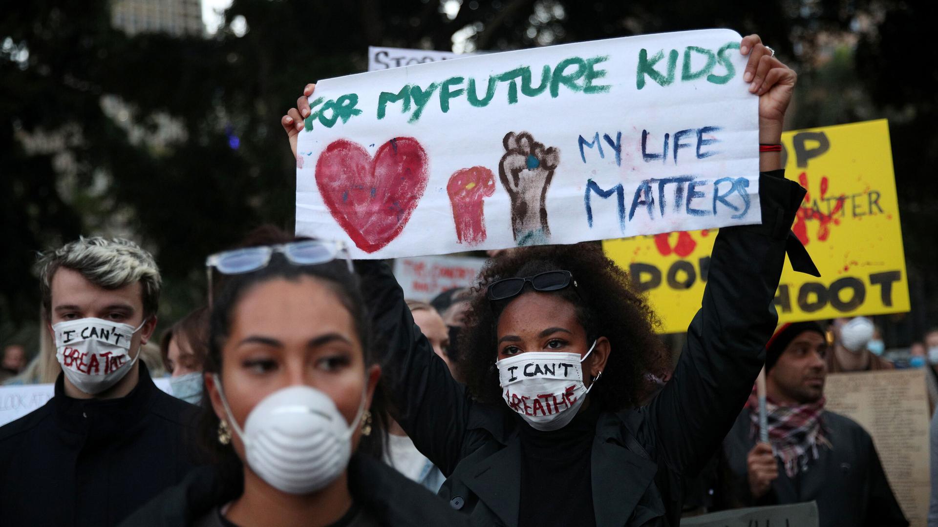 People protest, one woman with a sign "for my future kids my life matters" 