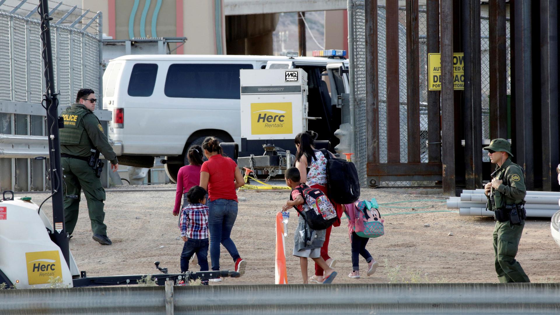 US Customs and Border Protection (CBP) agents look at women and children