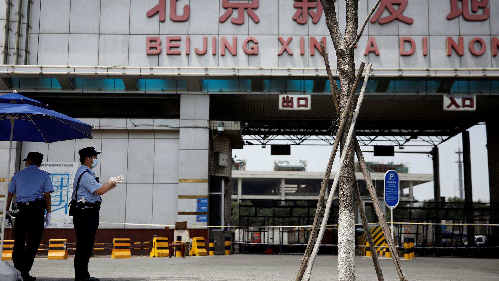 Two police officers are shown wearing protective face masks with the empty entrance to a food market in the background.