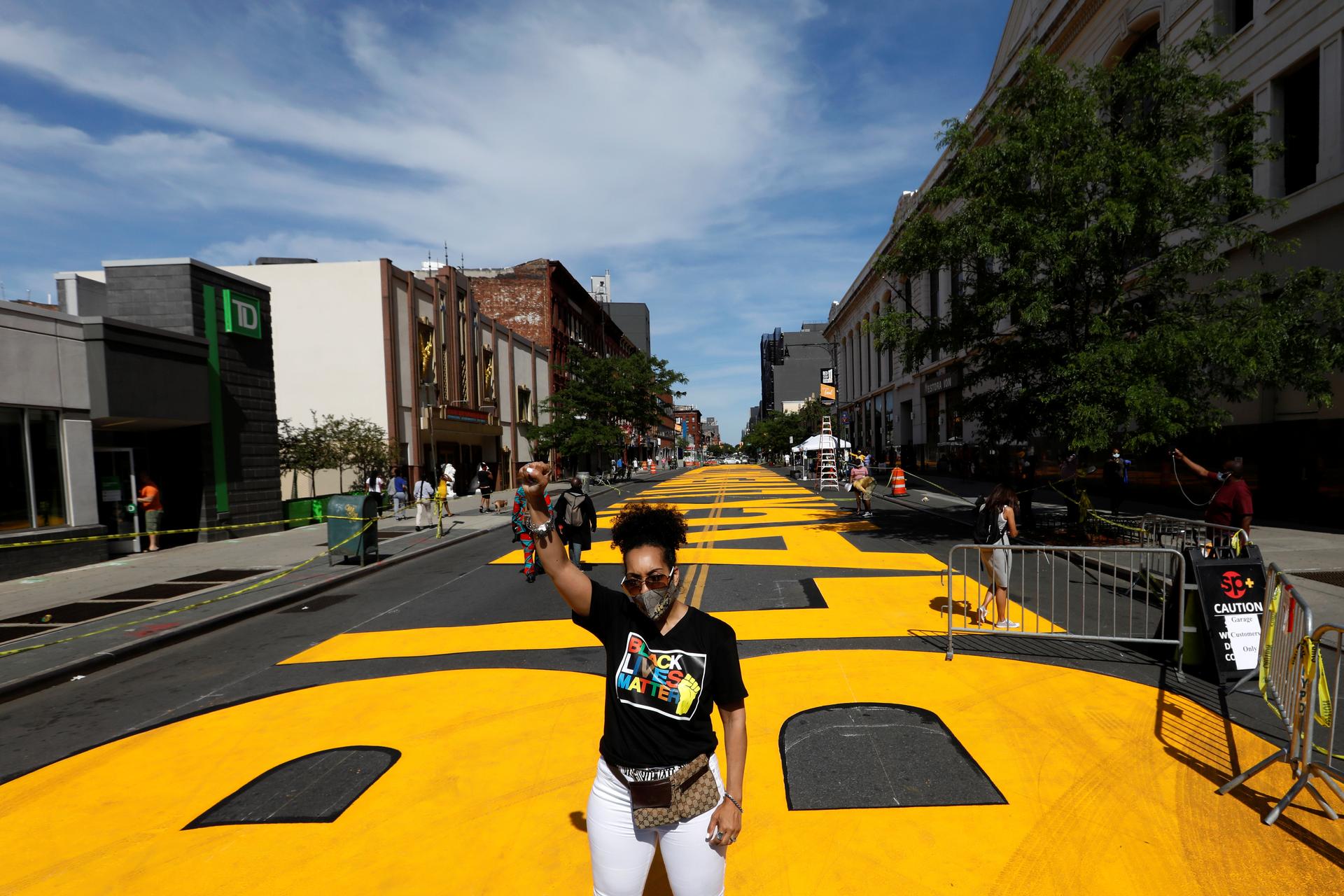 A woman poses in front of a Black Lives Matter mural on the street as a protest against racial inequality in the aftermath of the death in Minneapolis police custody of George Floyd, in Brooklyn, New York, June 16, 2020.  