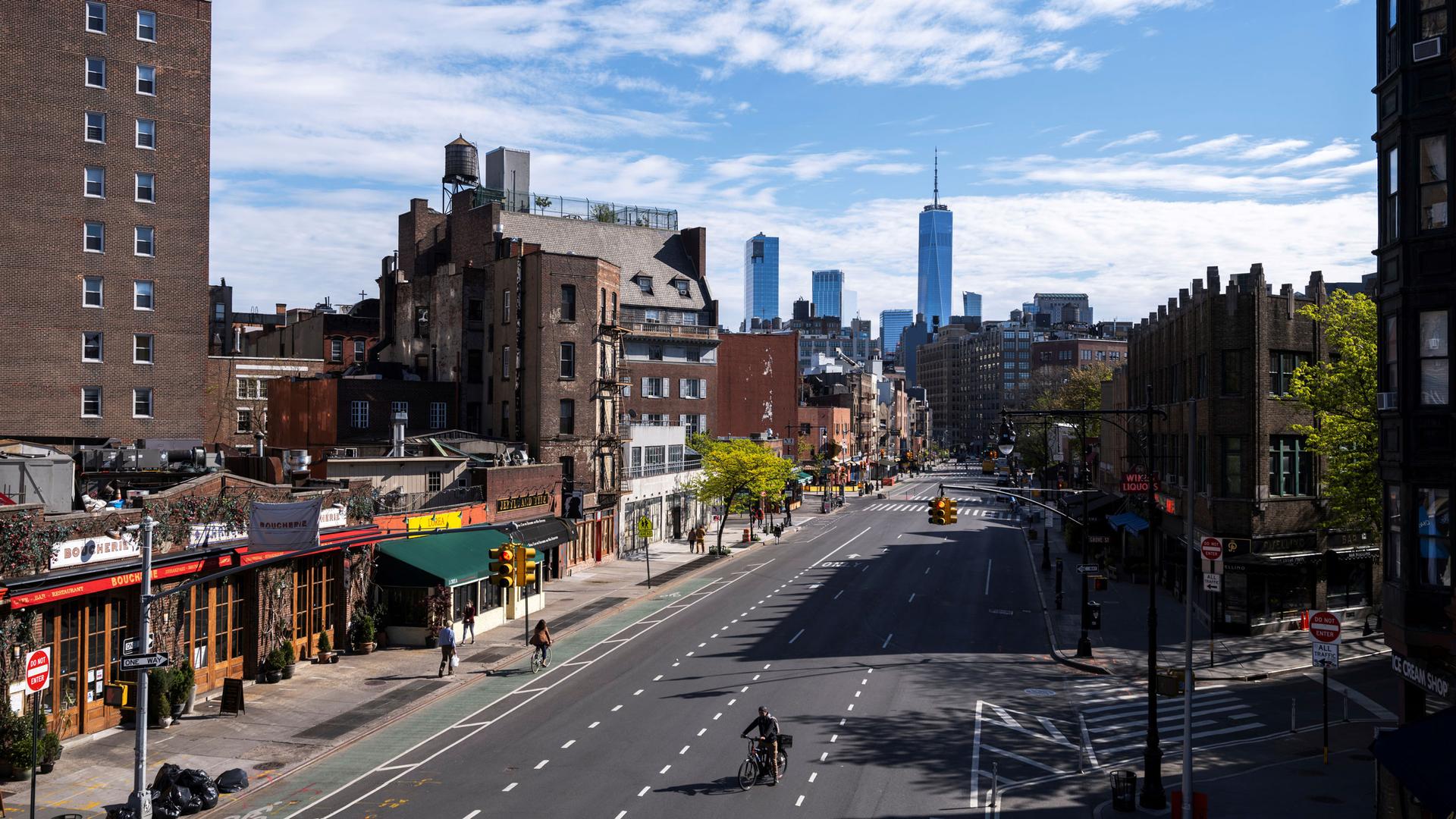 A cyclist is shown rides up a nearly empty three lanes of 7th Avenue with the Freedom Tower in the distance.
