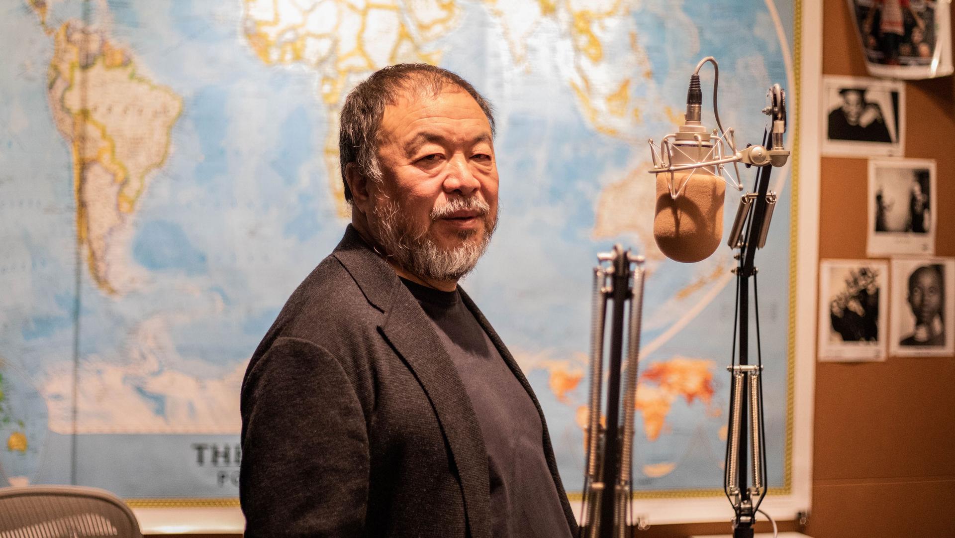 Ai Weiwei looks at the camera as he stands in front of a microphone