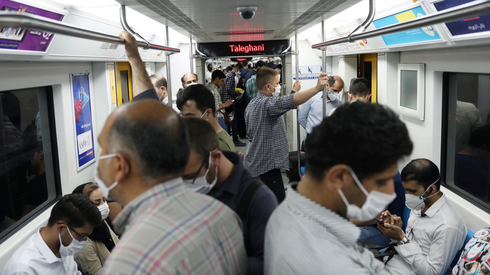Iranians wear protective face masks while riding on the metro crowded together