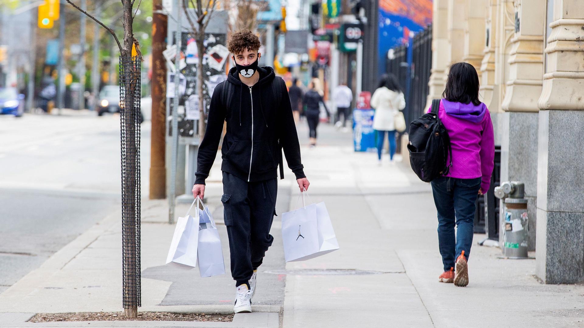 Nick Abrantes walks after purchased three pairs of shoes during a phased reopening from the coronavirus disease (COVID-19) restrictions in Toronto, Ontario, Canada May 19, 2020. REUTERS/Carlos Osorio/File Photo