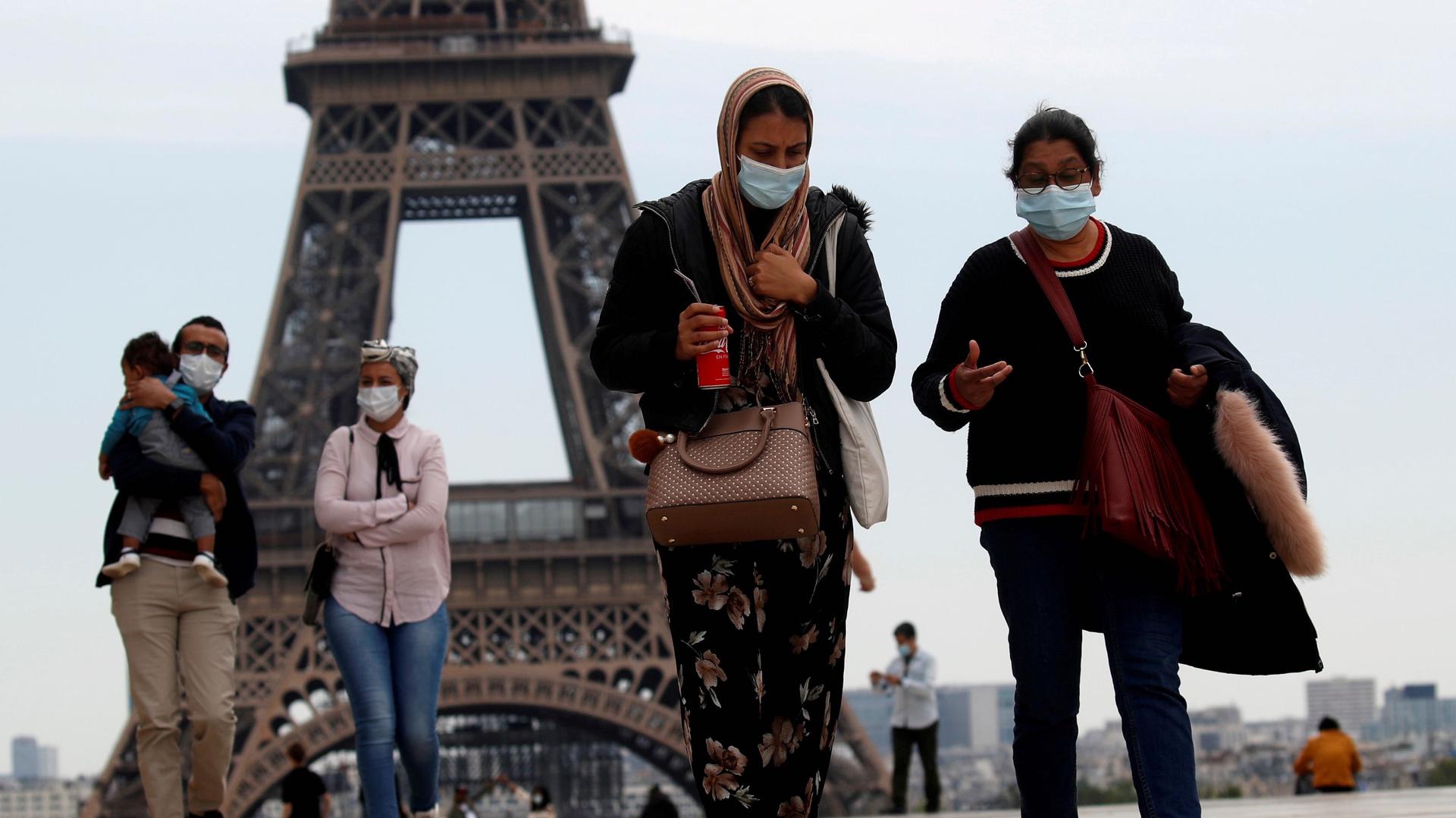 People wearing face masks walk at Trocadero square near the Eiffel Tower, as France began a gradual end to a nationwide lockdown due to the coronavirus disease (COVID-19) in Paris, May 16, 2020. 