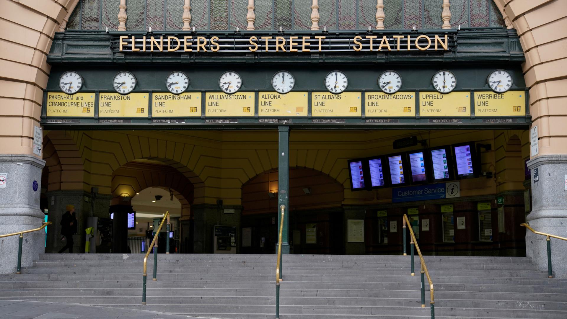 The entrance to Flinders Street train station is shown with nine clocks along the top and nearly empty of people.