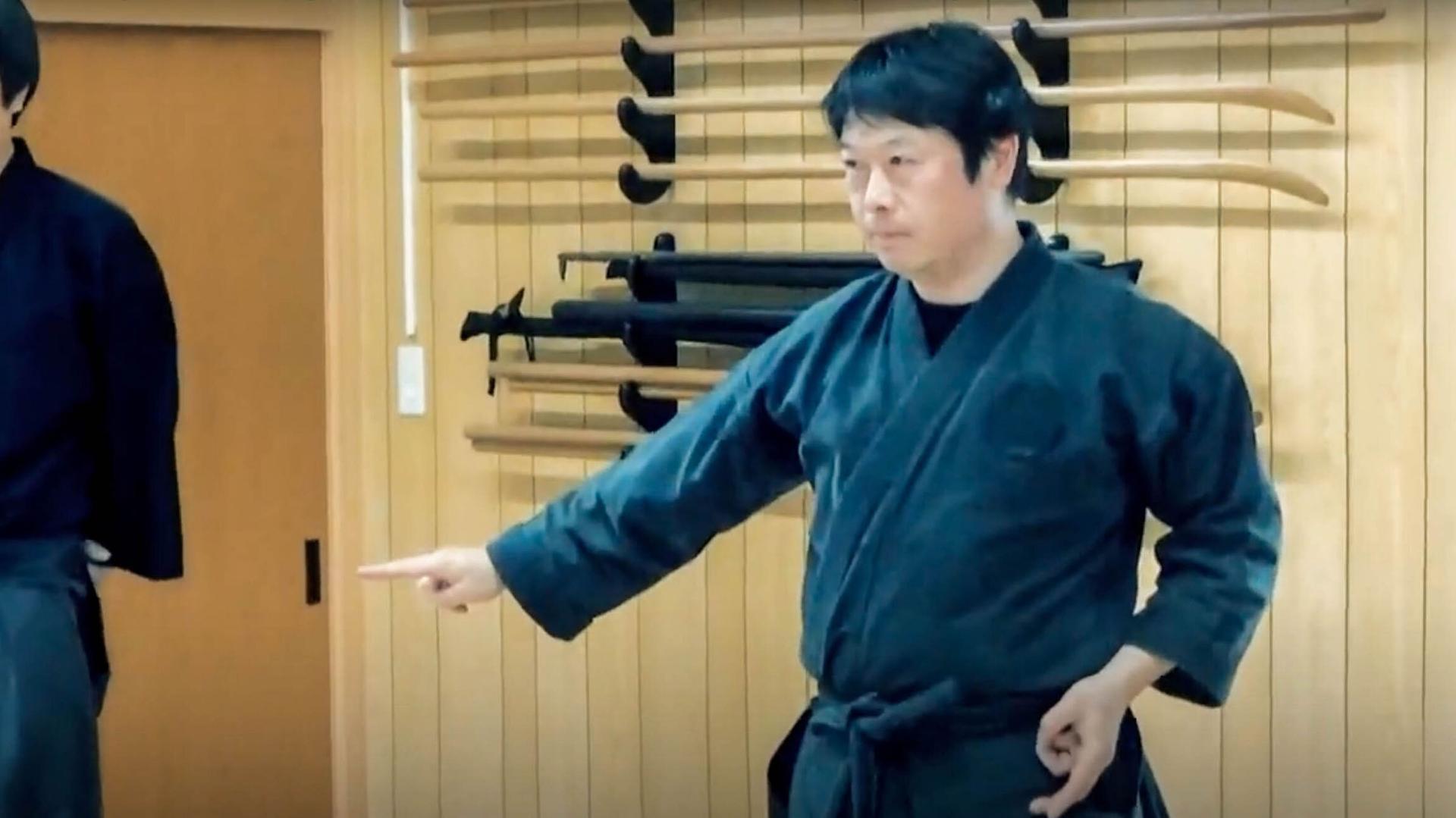 A man wears black and practices a ninja move.