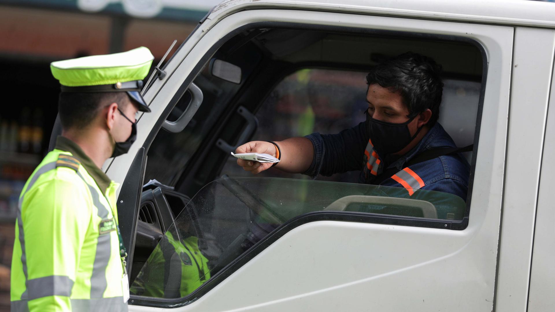 A police officer wearing a face mask asks for identification documents to a driver in one of the neighborhoods where the mayor's office decreed strict quarantine, amidst an outbreak of the coronavirus disease, in Bogota, Colombia, July 14, 2020.