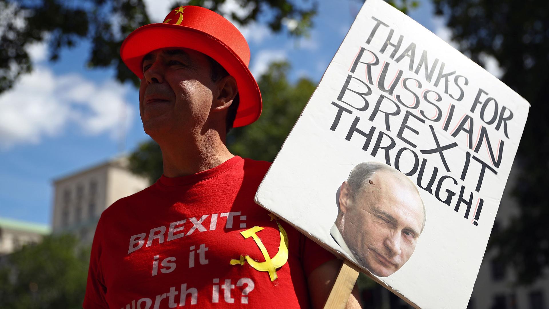 A man wearing a red top hat with the Russian hammer a sickle is shown holding a sign that says, "Thanks for the Russian Brexit through.
