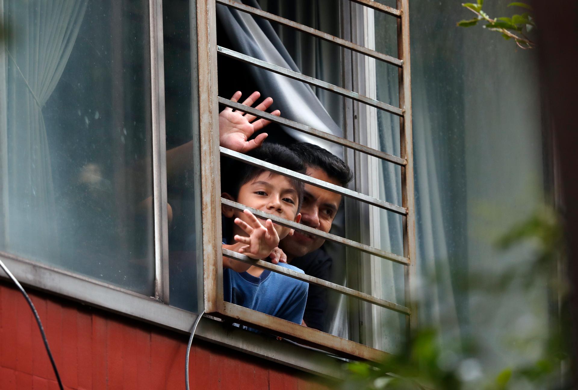 Residents wave from an apartment as Percibald García reads children's books aloud outside the high-rise buildings in the Tlatelolco housing complex, in Mexico City, Mexico, on July 18, 2020.