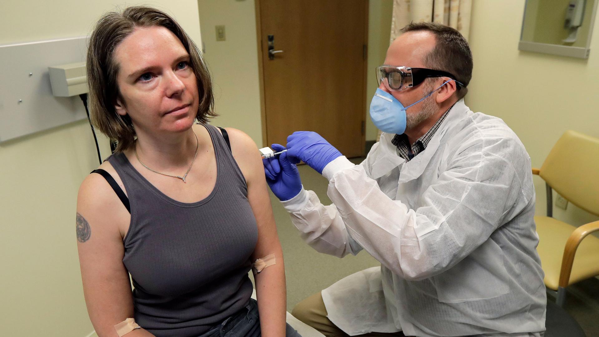 A woman is shown wearing a tank top and sitting while receiving an injection from a medical professional.
