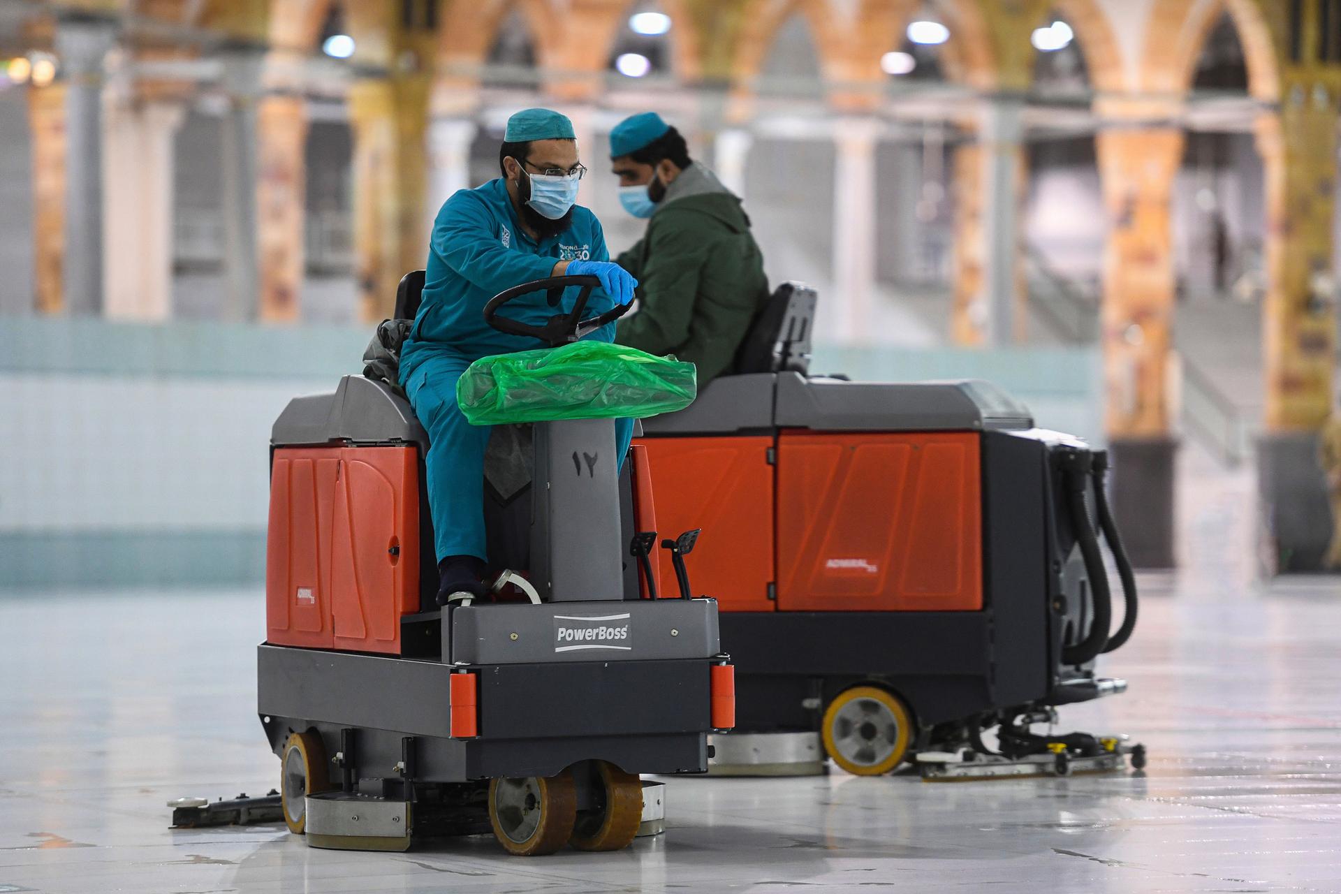 Two men are shown driving small machines that are polishing marble floors.