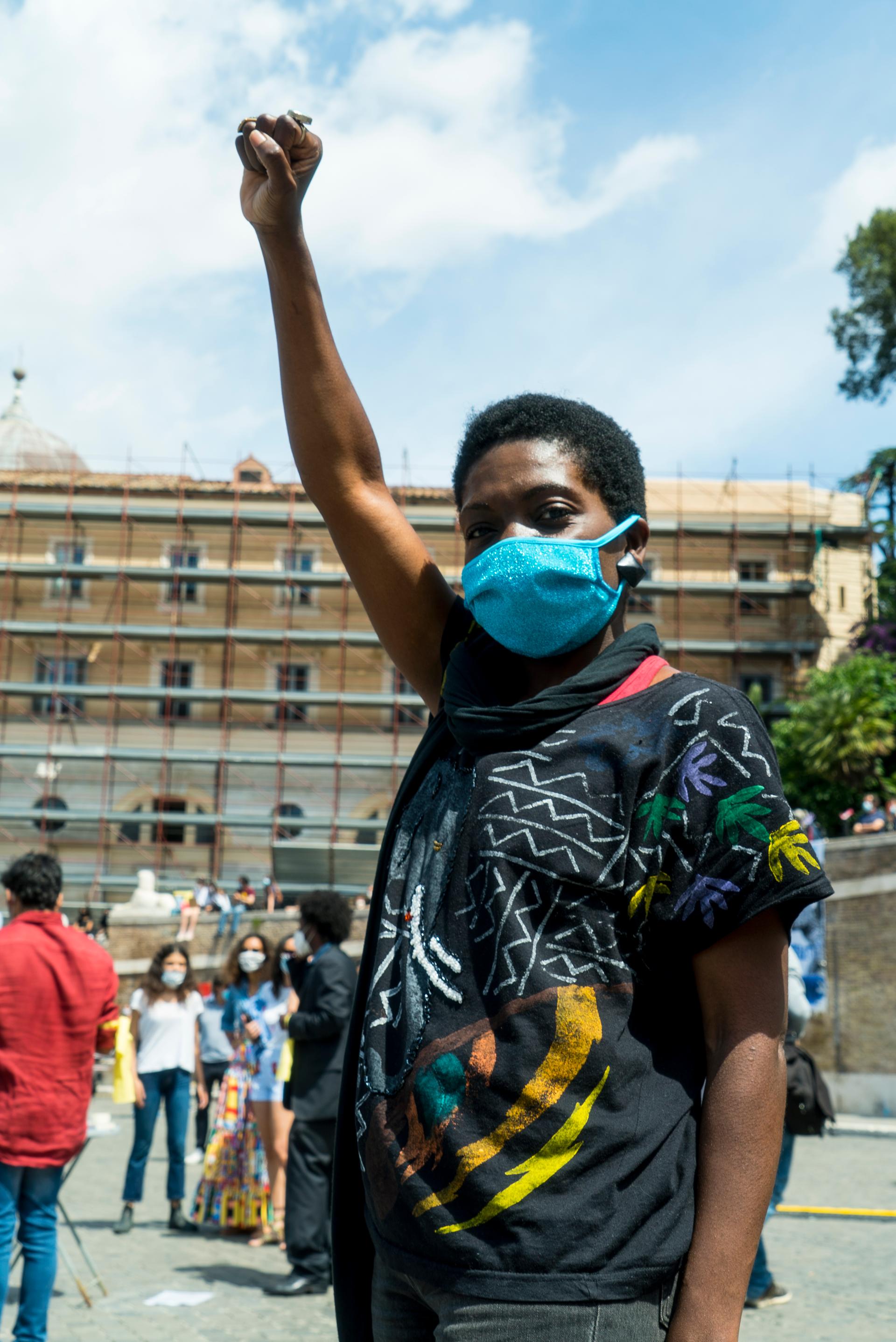 A Liberian woman with short afro wears a blue face mask at a protest
