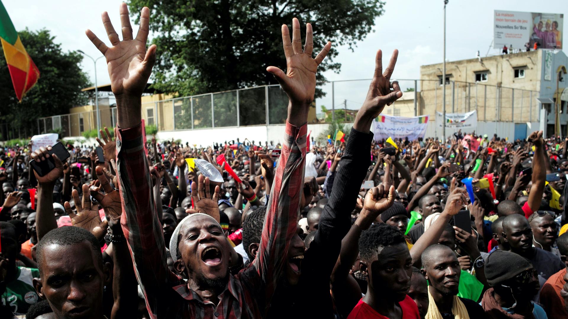 A huge crowd of protesters in Mali with one person raises his arms high in the air