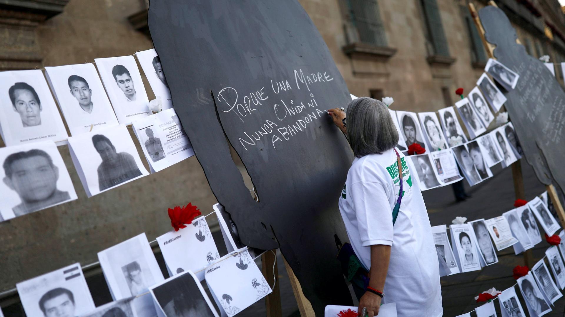 A woman wearing a white shirt signs a black silhouette during a demonstration for mothers of enforced disappearances 